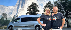 Brian and Michelle of LivinRVision in front of their campervan and scenic mountain view
