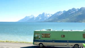 A Green RV traveling next to the coast